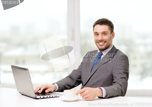 Image of smiling businessman with laptop and coffee