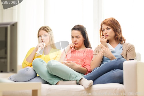 Image of three sad teenage girl watching tv at home