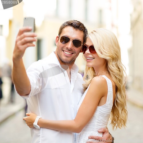 Image of smiling couple taking selfie with smartphone