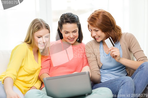 Image of smiling teenage girls with laptop and credit card