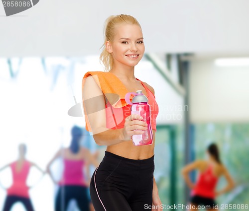 Image of smiling sporty woman with water bottle and towel