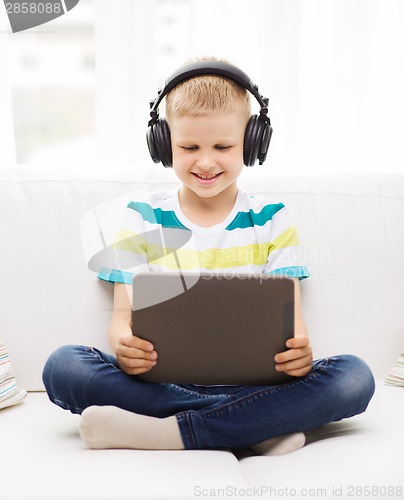 Image of little boy with tablet pc and headphones at home