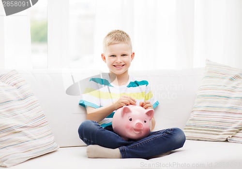 Image of smiling little boy with piggy bank and money