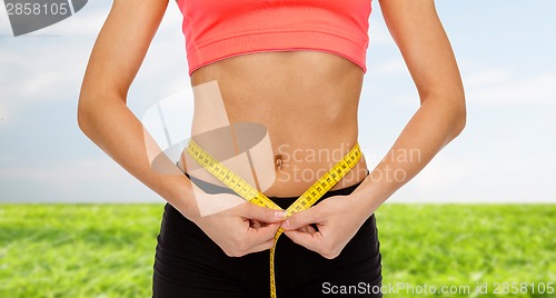 Image of close up of female hands measuring waist