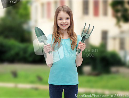 Image of smiling little girl with rake and scoop