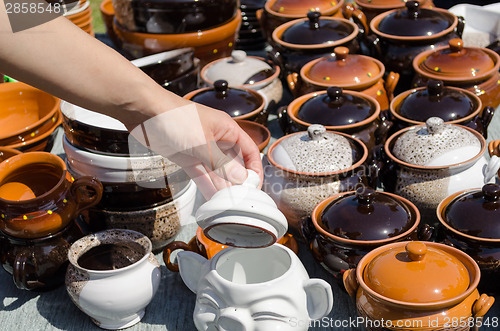 Image of handmade clay pots and woman hand hold clay lit  