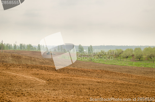 Image of wide plowed field in rural image with tractor  