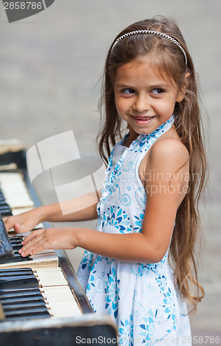Image of Little girl playing on a piano