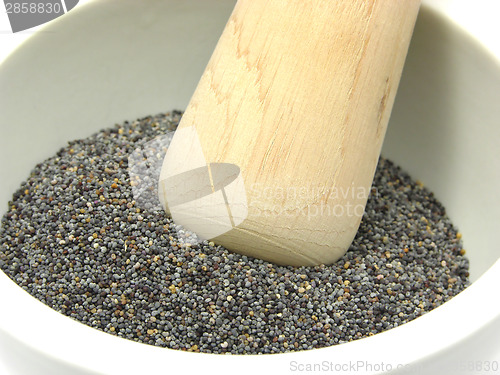 Image of Pestling poppy seeds  in a bowl of chinaware