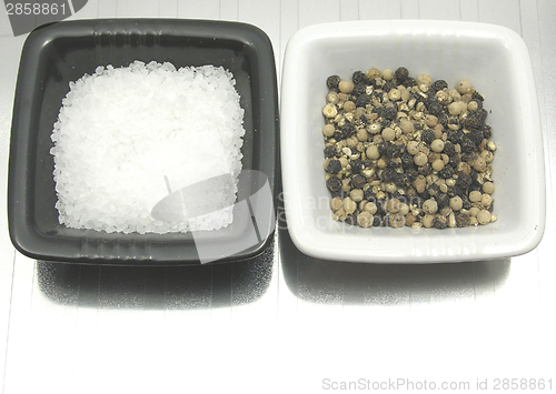 Image of Bowls of chinaware with salt and pepper on reflecting matting