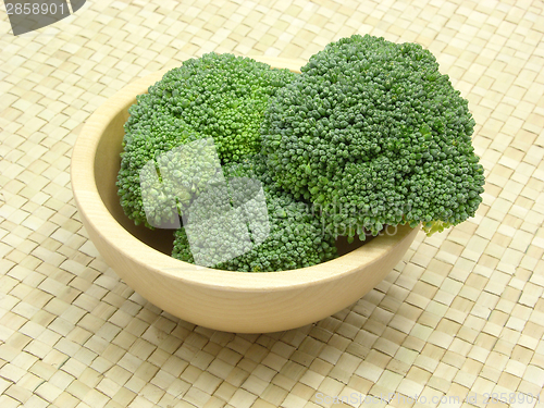 Image of Wooden bowl with broccoli on rattan underlay
