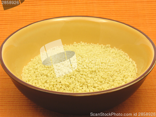 Image of Yellow couscous in a orange bowl of ceramic on an orange background