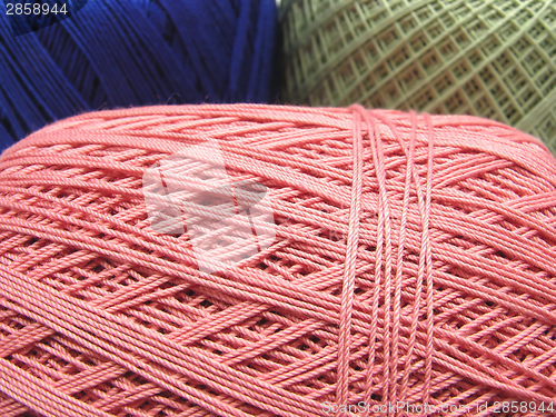 Image of Three balls of wool  in blue, pink and green in a close-up view