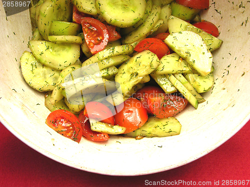 Image of Cucumbers and tomatoes with salat dressing in a bowl of ceramics