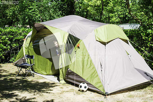 Image of Child peeks from a tent