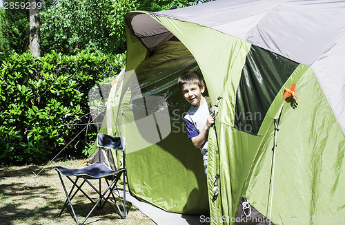 Image of Child peeks from a tent