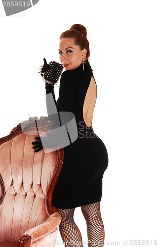 Image of Woman standing on armchair.