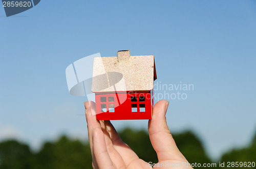 Image of hand hold house miniature on blue sky background 
