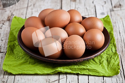 Image of  fresh brown eggs in plate and green napkin