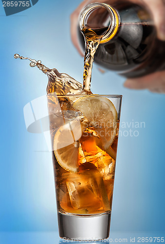 Image of Glass of splashing iced tea with lemon on blue background