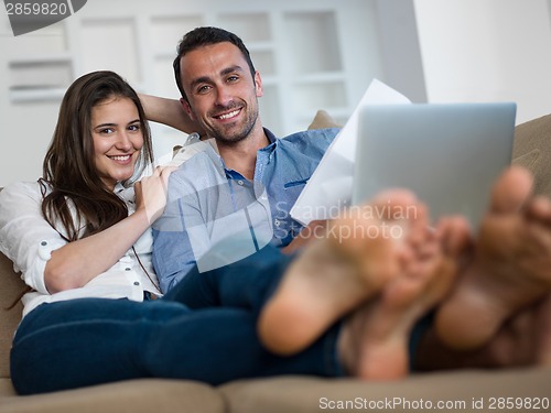 Image of relaxed young couple working on laptop computer at home