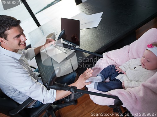 Image of man working from home and take care of baby