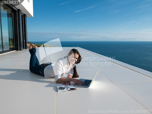 Image of relaxed young woman at home working on laptop