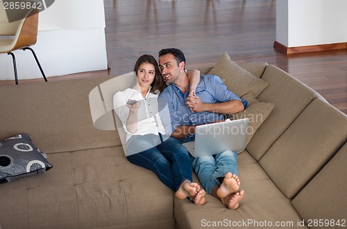 Image of relaxed young couple working on laptop computer at home