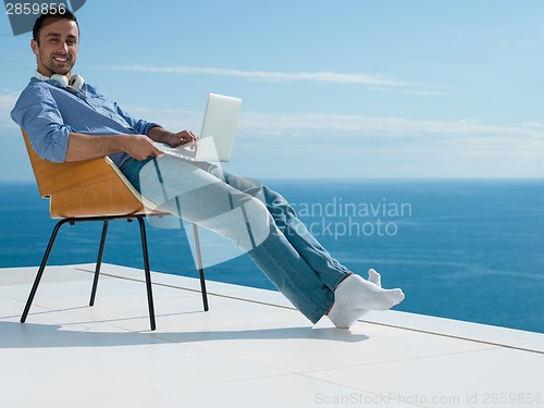 Image of relaxed young man at home on balcony