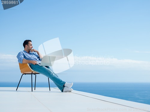 Image of relaxed young man at home on balcony