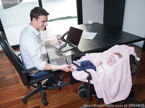 Image of man working from home and take care of baby