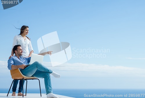 Image of relaxed young couple working on laptop computer at home