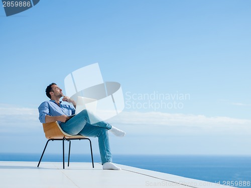 Image of relaxed young man at home on balcony