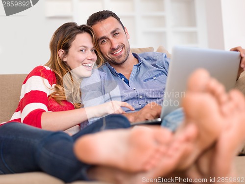 Image of relaxed young couple working on laptop computer at home