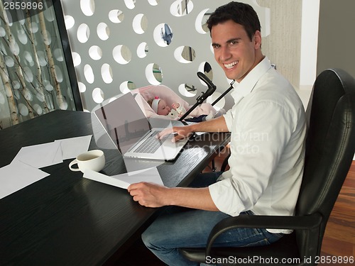 Image of man working from home and take care of baby