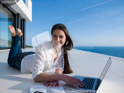 Image of relaxed young woman at home working on laptop