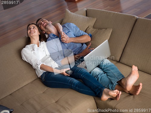 Image of relaxed young couple working on laptop computer at home