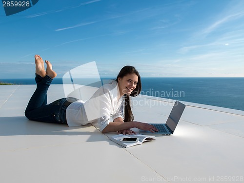 Image of relaxed young woman at home working on laptop