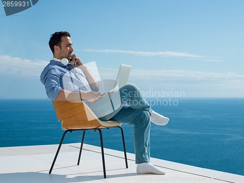 Image of relaxed young man at home on balcony