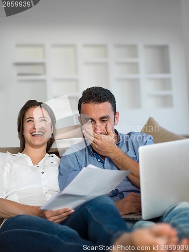 Image of relaxed young couple working on laptop computer at home