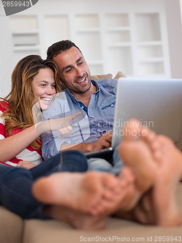 Image of relaxed young couple working on laptop computer at home