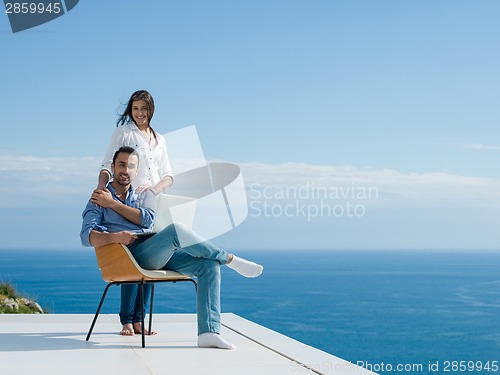 Image of relaxed young couple working on laptop computer at home