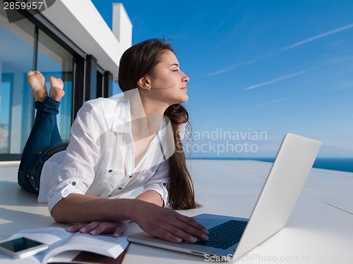 Image of relaxed young woman at home working on laptop