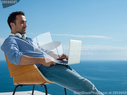 Image of relaxed young man at home on balcony