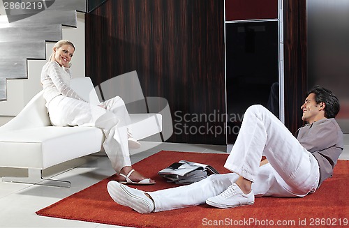 Image of happy couple sitting on sofa and floor