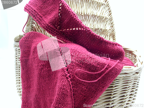 Image of Red knitting with whole pattern in a wooden basket