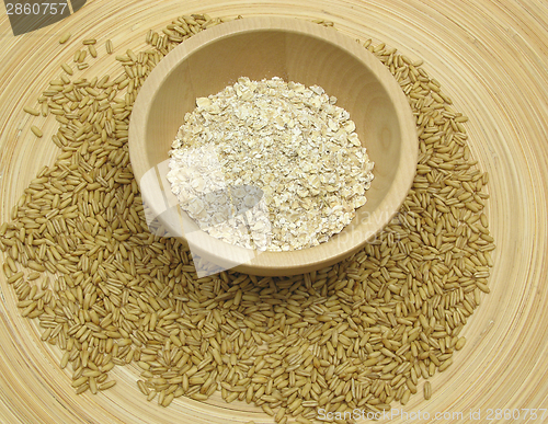 Image of Wooden bowl with oat flakes and corn on bamboo plate