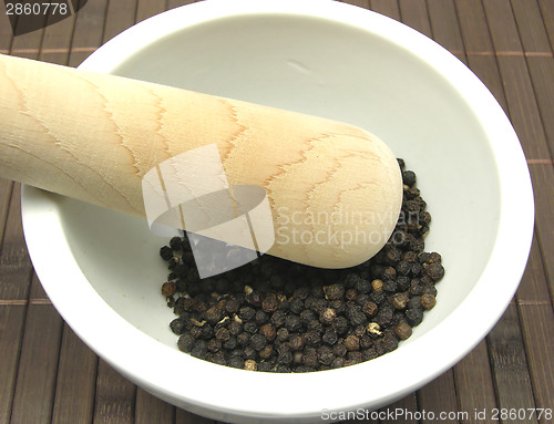 Image of Pestling black peppercorns  in a bowl of chinaware