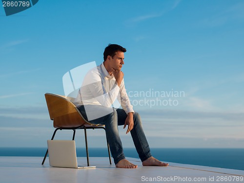 Image of relaxed young man at home on balcony