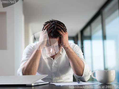 Image of frustrated young business man working on laptop computer at home